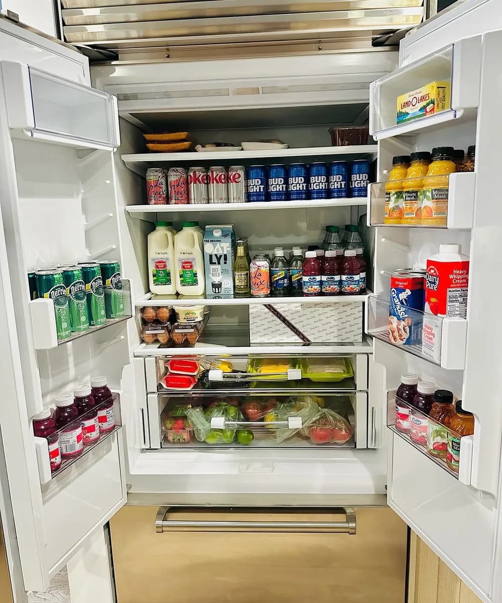 A vacation rental refrigerator filled with groceries, fresh produce, and drinks